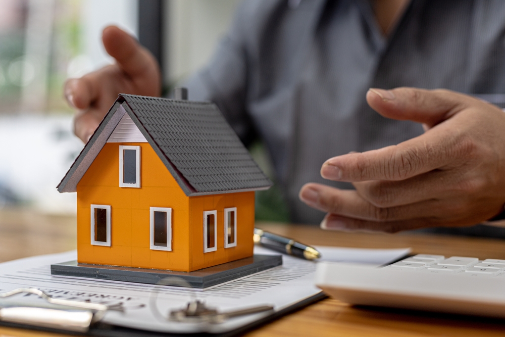 A man on the home buyer's journey viewing a model of a home on top of paperwork.
