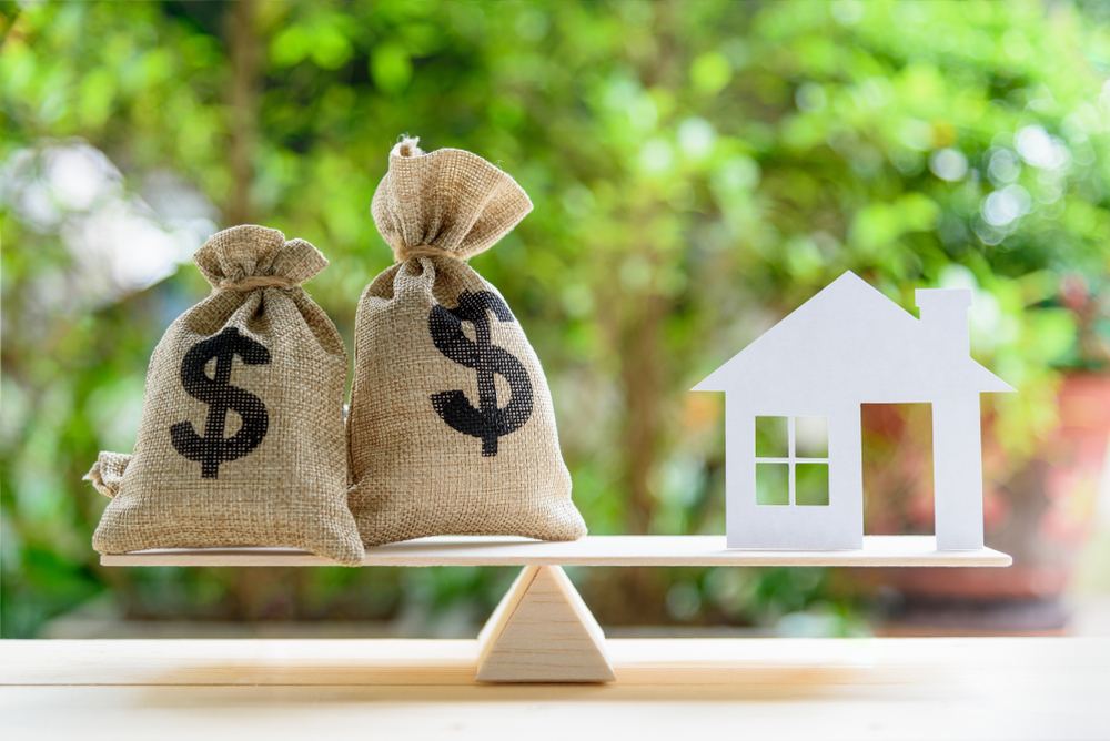house of a model and money on a scale representing home equity.